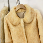 Close-up of fluffy round doll collar on solid cream real rabbit fur short coat
