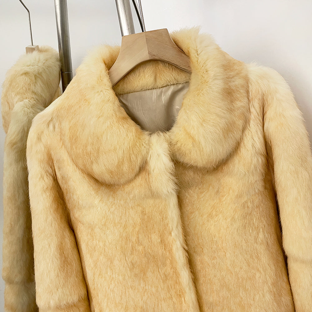 Close-up of fluffy round doll collar on solid cream real rabbit fur short coat