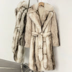 Elegant long cream vegan fur overcoat showing the cinched belted waist