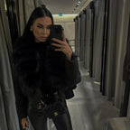 Woman wearing a black luxury cropped puffer jacket with a massive black real fox fur collar