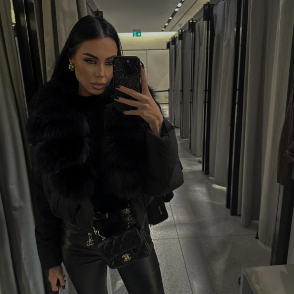 Woman wearing a black luxury cropped puffer jacket with a massive black real fox fur collar
