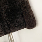 Close-up of premium curly 100% real lamb wool shearling texture in dark chocolate