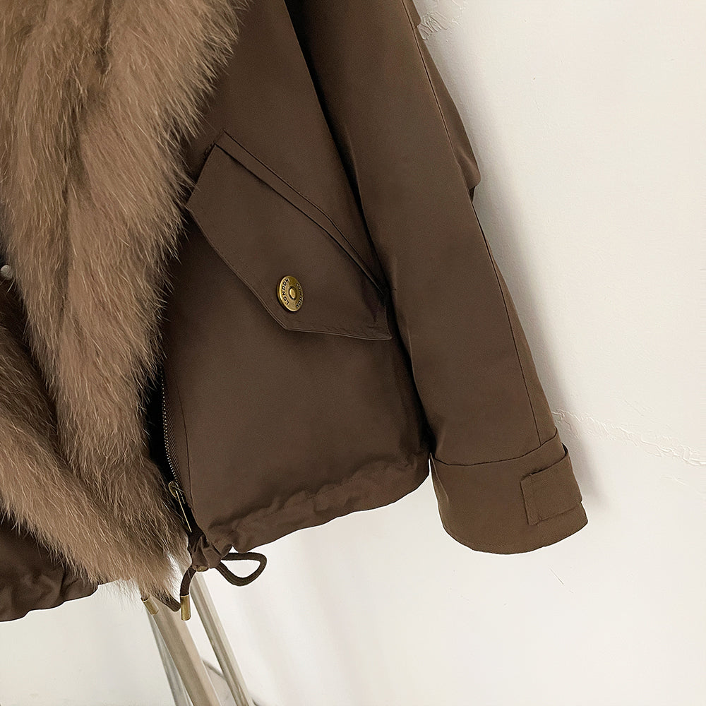 Detail shot of brass snap cargo pocket and adjustable cuffs on down jacket